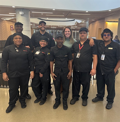 DU Dining partners with local nonprofit to offer refugees jobs—and a bridge to a new life Refugees working in DU Dining and Sodexo employee Whitney Couzens pose for a photo.