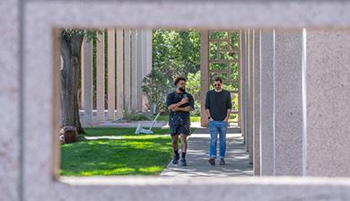 Two male students walk along a campus path.