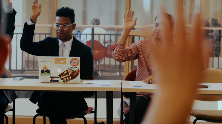 students in class with hands raised