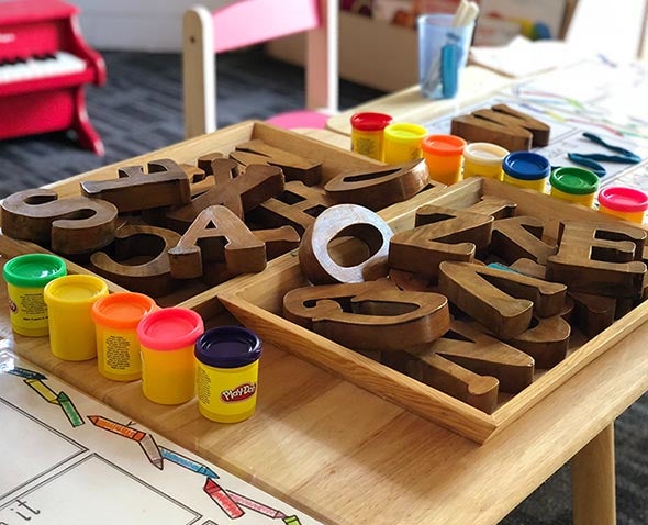 playdough and wooden letters in box on table