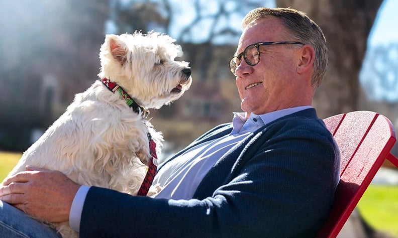 man and dog in chair outside