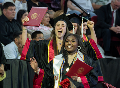 Students in graduation regalia celebrating at Undergraduate Commencement