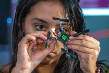 A girl in a STEM lab holds a piece of equipment close to her face. 