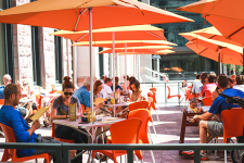 Folks sitting outside the Snooze location at Union Station under orange umbrellas