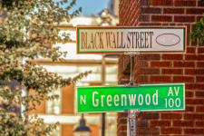 Two street signs, one that reads Black Wall Street, and the other that reads Greenwood.