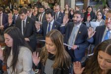 A group of law students hold up their right hands as they are sworn in as new student attorneys.