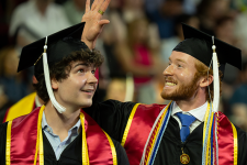 Two students in graduation regalia at 2024 Undergraduate Commencement