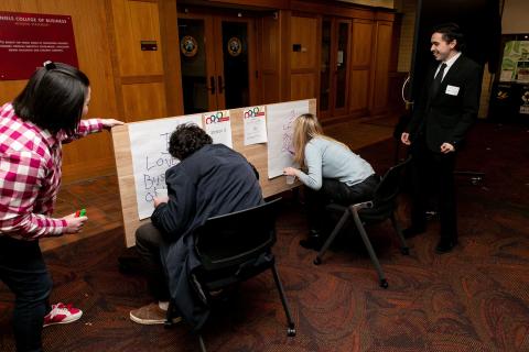 Students draw on large pieces of paper during the DU undergrad business olympics.