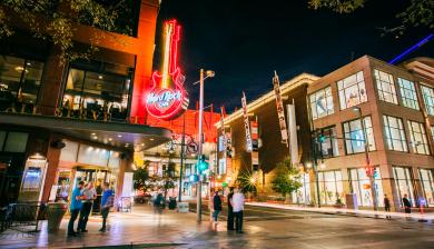 A nighttime view of 16th Street Mall in Denver Colorado with the Hard Rock Cafe sign in the background. 