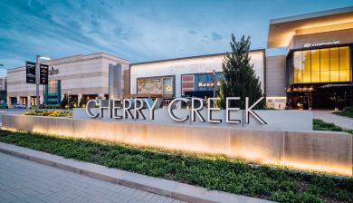 A sign reads Cherry Creek with the Cherry Creek Shopping Center in the background.