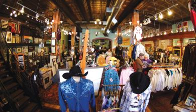 An interior view of Rockmount in Denver Colorado with cowboy shirts and hats on shopping racks. 