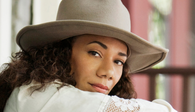 Martha Redbone in a large cream hat.