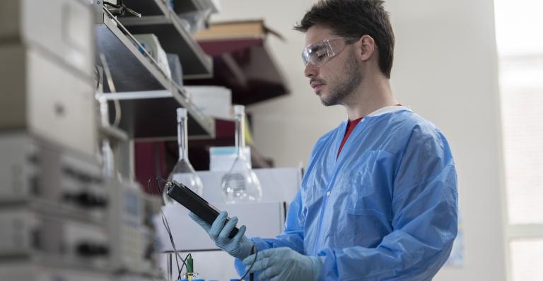 A student researcher works with a microscope in a lab.