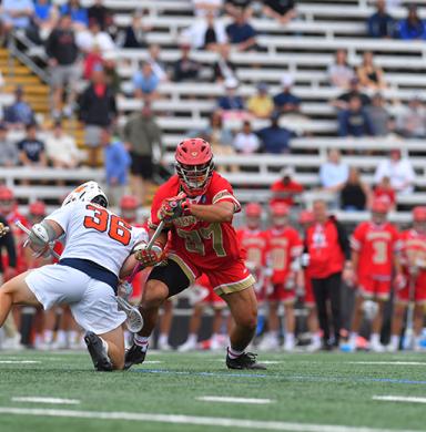 A DU men's lacrosse player runs with the ball.