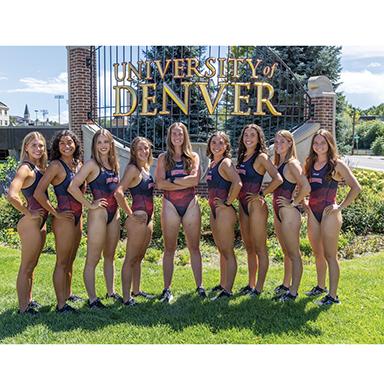 The women's triathlon team poses for a photo in front of the University of Denver sign.