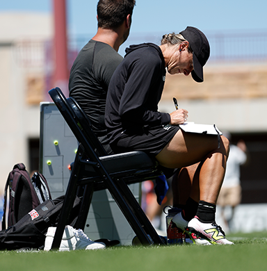 Head coach Julianne Sitch writes notes down on a notepad. 